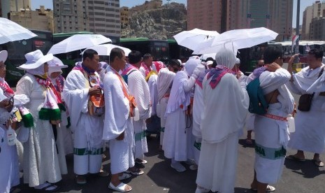 Jamaah haji menggunakan payung akibat cuaca yang sangat terik di Pos Terminak Syib Amir  Makkah, Senin (5/8).  Cuaca di Makkah pada siang hari mencapai 41 derajat Celsius dan malam 33 derajat Celsius 