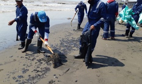 Petugas Pertamina dibantu warga, sedang membersihkan ceceran spill oil di Pantai Cemara, Desa Cemarajaya, Kecamatan Cibuaya, Rabu (7/8). Pencemaran limbah minyak ini, sudah terjadi hampir sebulan. 