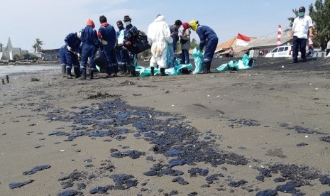 Petugas Pertamina dibantu warga, sedang membersihkan ceceran spill oil di Pantai Cemara, Desa Cemarajaya, Kecamatan Cibuaya, Rabu (7/8). Pencemaran limbah minyak ini, sudah terjadi hampir sebulan. 