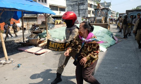 Petugas Satpol PP menghalau pedagang yang menolak tempat berjualannya dibongkar pada proses penertiban.