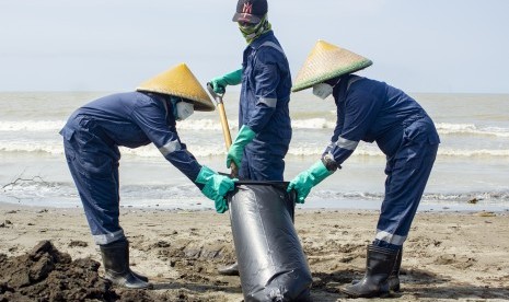 Petugas mengumpulkan tumpahan minyak mentah yang tercecer di Pesisir Pantai Mekarjaya, Karawang, Jawa Barat, Kamis (8/8/2019).