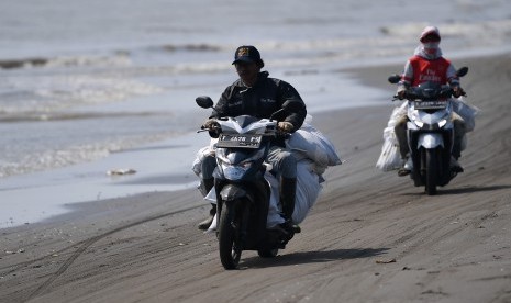 Warga membawa karung berisi ceceran minyak mentah yang berhasil dikumpulkan di Pantai Tanjungsari, Karawang, Jawa Barat, Kamis (8/8/2019). 