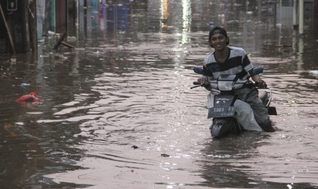 Seorang pengendara motor yang mogok karena banjir. Ilustrasi.