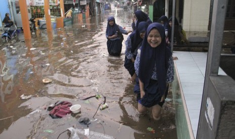 Korban banjir Depok mengungsi di masjid dan hotel. Foto: Sejumlah anak sekolah melintasi banjir di Depok, Jawa Barat, Kamis (15/8/2019).