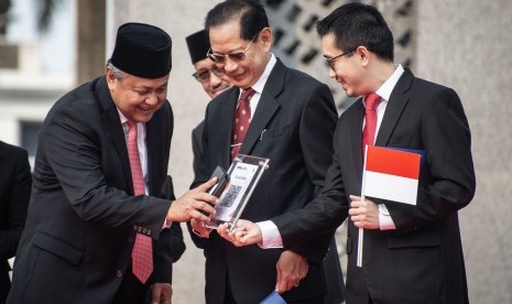 Gubernur Bank Indonesia (BI) Perry Warjiyo (kiri) disaksikan Presiden Direktur BCA Jahja Setiaadmadja (tengah) dan CEO LinkAja Danu Wicaksana (kanan) melakukan tap in dalam peluncuran QR Code Indonesian Standard (QRIS) di halaman Gedung Bank Indonesia, Jakarta, Sabtu (17/8/2019). 