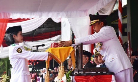 Wali Kota Yogyakarta, Haryadi Suyuti menyerahkan bendera  kepada pembawa bendera, Tsana Aqila U untuk dikibarkan pada upacara  peringatan kemerdekaan Indonesia ke 74 di Balai Kota Yogyakarta