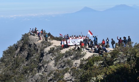 Pendaki mengibarkan bendera Merah Putih sambil menyanyikan lagu kebangsaan Indonesia Raya saat memperingati Hari Ulang Tahun ke-74 Proklamasi Kemerdekaan RI di kawasan Puncak Gunung Lawu Magetan, Jawa Timur. Ilustrasi