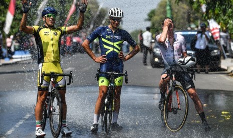 Sejumlah pebalap sepeda membahasi dirinya dengan air seusai finish etape pertama Tour de Indonesia 2019 di alun-alun Kabupaten Ngawi, Jawa Timur, Senin (19/8/2019).