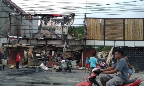 Warga membersihkan puing sisa kerusuhan di salah satu gedung yang terbakar di Manokwari, Papua Barat, Selasa (20/8/2019).