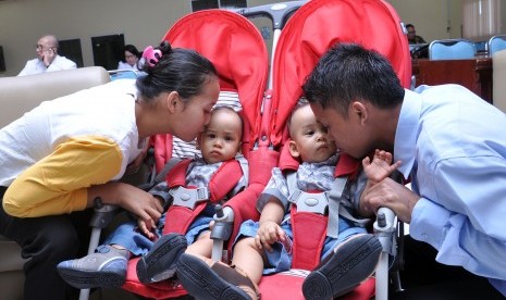 Orang tua bayi kembar siam Juliadi Silitonga (kanan) dan Nurida Sihombing (kiri) mencium anaknya sebelum dibawa pulang dari di RSUP H Adam Malik Medan, Sumatera Utara, Senin (26/8/2019).