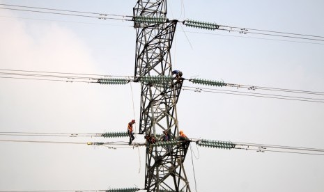 Pekerja memasang instalasi listrik di menara Saluran Udara Tegangan Ekstra Tinggi (SUTET) 