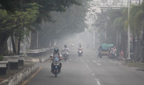 Sejumlah pengendara melintas di jalan yang diselimuti asap dari kebakaran hutan di Kota Dumai, Dumai, Riau, Rabu (28/8/2019). 