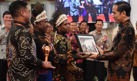 Presiden Joko Widodo (kanan) menerima foto dari peserta pemenang kategori khusus pada Festival Gapura Cinta Negeri dari Nduga di Istana Negara Jakarta, Senin (2/9/2019). 