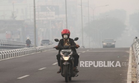 Pengendara sepeda motor menembus kabut asap pekat dampak dari kebakaran hutan dan lahan yang menyelimuti Kota Pekanbaru, Riau, Senin (9/9/2019) pagi.