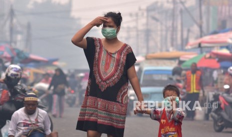 Seorang ibu dan anaknya mengenakan masker medis saat asap kebakaran hutan dan lahan (Karhutla) menyelimuti Kota Pekanbaru, Riau, Selasa (10/9/2019