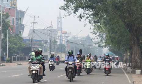 Sejumlah pengendara motor melintasi jalan yang diselimuti kabut asap di Pontianak, Kalimantan Barat, Selasa (10/9/2019).