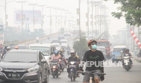 Warga bersepeda menggunakan masker pelindung pernapasan ketika melintas di jalan Ahmad Yani yang terpapar kabut asap di Banjarmasin, Kalimantan Selatan, Ahad (15/9/2019).