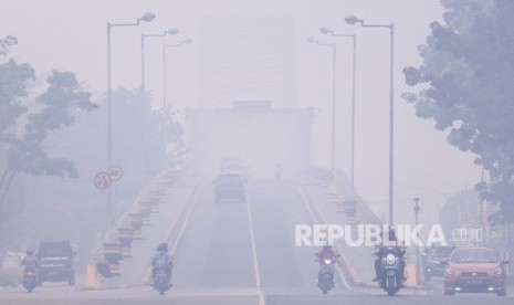 Pengendara melintas di Jembatan Kahayan yang diselimuti kabut asap di Palangka Raya, Kalimantan Tengah.