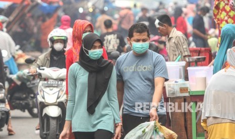 Warga beraktivitas mengenakan masker medis ketika kabut asap Karhutla menyelimuti Kota Pekanbaru, Riau, Ahad (15/9/2019).