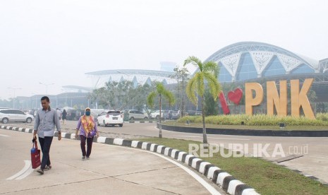 Warga berjalan di kompleks Bandara Supadio yang diselimuti kabut asap di Kabupaten Kubu Raya, Kalimantan Barat, Ahad (15/9/2019).