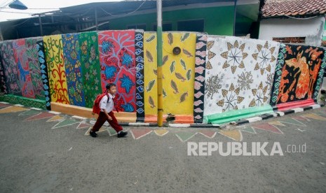 Seorang siswa sekolah melintas di samping mural bermotif batik di Jalan Neglasari, Kota Bogor, Jawa Barat, Senin (16/9/2019).