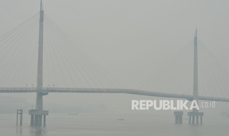 Warga menggunakan perahu menyeberangi Sungai Batanghari di bawah Jembatan Gentala Arasy yang diselimuti kabut asap karhutla, Jambi (ilustrasi)