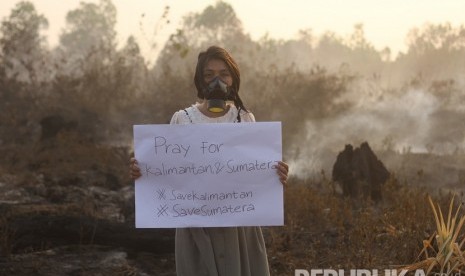 Warga berpose membawa poster bertuliskan keprihatinan kebakaran hutan dan lahan di kawasan Landasan Ulin, Banjarbaru, Kalimantan Selatan, Kamis (19/9/2019). 