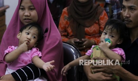 Bayi kembar siam Aqila (kiri) digendong ibunya Silvina Dewi dan Azila (kanan) digendong bapaknya Jayasri saat acara syukuran atas keberhasilan pemisahan bayi kembar siam asal Kendari, Sulawesi Tenggara, di Rumah Sakit Umum Daerah (RSUD) Dr Soetomo, Surabaya, Jawa Timur, Jumat (20/9/2019).