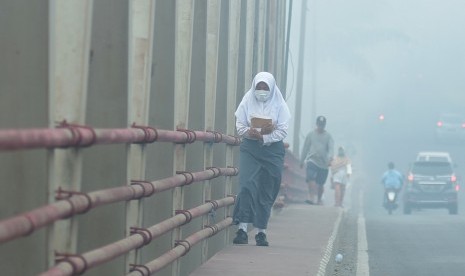 Seorang siswa mengenakan masker saat berjalan menyusuri jembatan, di Palembang, Sumatera Selatan, Senin (23/9/2019). 