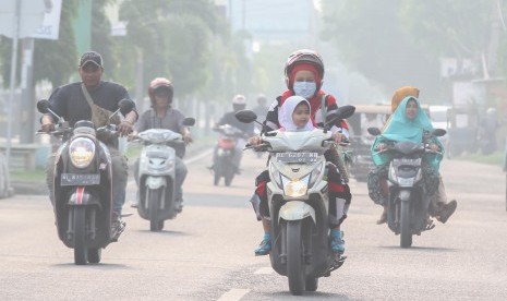 Warga tidak memakai masker mengabaikan kesehatan melewati polusi asap yang menyelimuti jalan Pase, Kota Lhokseumawe, Aceh, Selasa (24/9/2019). 