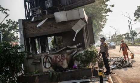 Petugas Polisi dan PPSU beraktivitas di dekat Pos Polisi yang hangus terbakar pascaunjuk rasa mahasiswa di Jalan Gerbang Pemuda, Senayan, Jakarta, Rabu (25/9/2019).