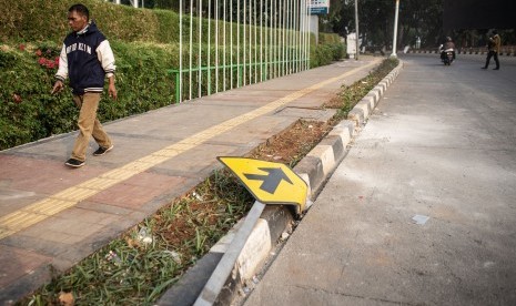 Warga berjalan di dekat rambu lalu lintas yang rusak pascaunjuk rasa mahasiswa di Jalan Gatot Subroto, Slipi, Jakarta, Rabu (25/9/2019). 