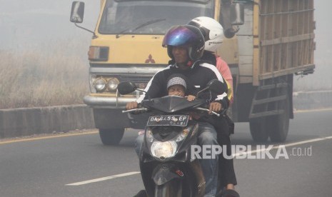 Pengendara motor melintas di jalan lingkar selatan yang diselimuti kabut asap.