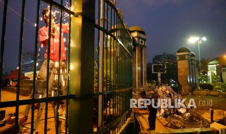 Pekerja memperbaiki pagar pascaaksi unjuk rasa mahasiswa menolak Undang-Undang KPK hasil revisi dan rencana pengesahan Rancangan Kitab Undang-Undang Hukum Pidana (RKUHP) di Gedung DPR/MPR, Senayan, Jakarta, Rabu (25/9/2019).