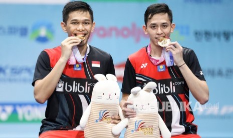 Ganda putra Indonesia Fajar Alfian (kiri) dan Muhammad Rian Ardianto menggigit medali di atas podium seusai keluar sebagai juara setelah mengalahkan ganda putra Jepang Takeshi Kamura dan Keigo Sonoda pada final Korea Open 2019 di Incheon Airport Skydome, Korea Selatan, Ahad (29/9/2019).