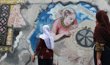 Dua orang siswi mengamati mural bergambar perajin batik yang ada di Kampung Batik Tangerang, Larangan, Tangerang, Banten, Rabu (2/10/2019). 