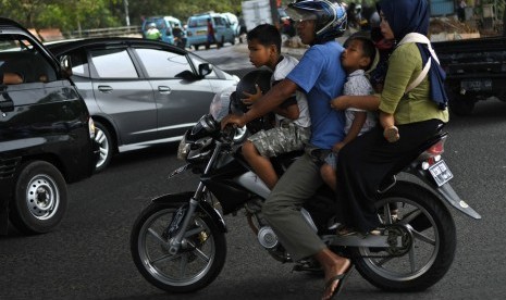 Pesepeda motor memboncengkan empat penumpang tanpa helm saat melintas di Jalan Raya Bogor. (Ilustrasi)