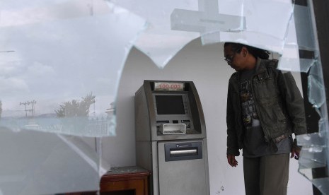 Seorang warga mengamati mesin Anjungan Tunai Mandiri (ATM) bersama yang rusak di kompleks Kantor Bupati Jayawijaya, Wamena, Papua, Rabu (9/10/2019). 