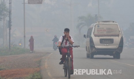 Pelajar SDN 61 Kabupaten Tanjungjabung Timur dan warga beraktivitas di Jalan Lintas Jambi-Muara Sabak yang diselimuti kabut asap karhutla di Muara Sabak Barat, Tanjungjabung Timur, Jambi.