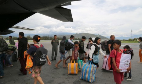 Sejumlah pengungsi mengangkat barang bawaannya ketika tiba dengan menumpang pesawat Hercules TNI AU di Bandar Udara Wamena, Papua, Rabu (9/10/2018).