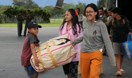 Sejumlah pengungsi mengangkat barang bawaannya ketika tiba dengan menumpang pesawat Hercules TNI AU di Bandar Udara Wamena, Papua, Rabu (9/10/2018).