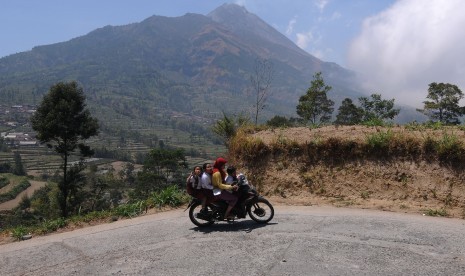 Warga melintas dengan latar belangkang Gunung Merapi di kawasan Selo, Boyolali, Jawa Tengah, Selasa (15/10/2019). 