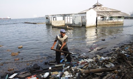 Warga memilah sampah dengan latar bangunan yang tergenang rob (air pasang laut) di Muara Baru, Jakarta Utara.