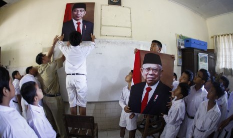 Siswa SD Negeri Joglo Solo dibantu guru memasang foto Presiden Joko Widodo dan dan Wakil Presiden Ma'ruf Amin di ruang kelas sekolahnya di Solo, Jawa Tengah, Senin (21/10/2019). 