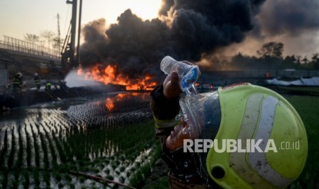 Seorang pemadam kebakaran membasuh mukanya saat berusaha memadamkan kebakaran pipa minyak milik PT Pertamina di Melong, Cimahi, Jawa Barat, Selasa (22/10/2019).