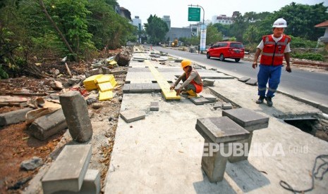 Pekerja melakukan pengerjaan pelebaran trotoar di kawasan Kemang, Jakarta Selatan.