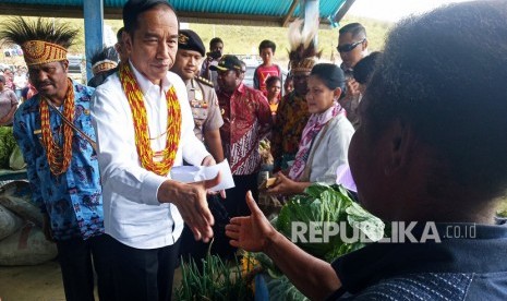 Presiden Joko Widodo (kedua kiri) bersama Ibu Negara Iriana Joko Widodo (ketiga kanan) menyapa warga saat meninjau pasar khusus Mama Papua di Distrik Anggi, Kabupaten Pegunungan Arfak, Papua Barat, Ahad (27/10/2019). 