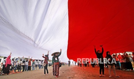 Warga membentangkan bendera Merah Putih saat memperingati Hari Sumpah Pemuda di kampung nelayan Greges, Surabaya, Jawa Timur, Ahad (27/10/2019). 