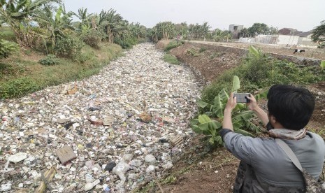 Jurnalis mengambil gambar aliran Kali Jambe di Perumahan Satria Jaya Permai yang dipenuhi sampah, Kabupaten Bekasi, Jawa Barat, Selasa (29/10/19).