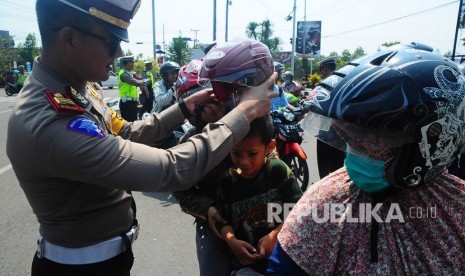 Anggota kepolisian memakaikan helm yang dibagikan secara gratis kepada pelanggar lalu lintas saat Operasi Zebra (ilustrasi).